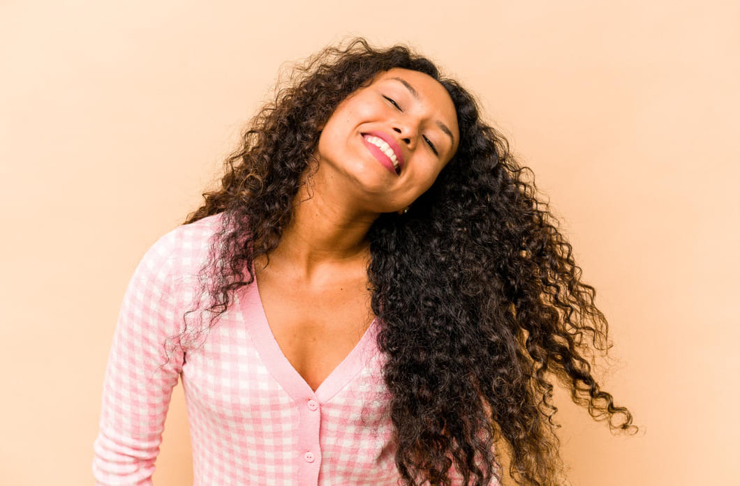 mulher-morena-de-blusa-rosa-sobre-um-fundo-rosa-de-cabelos-cacheados-representando-as-curvaturas-3a-3b-3c