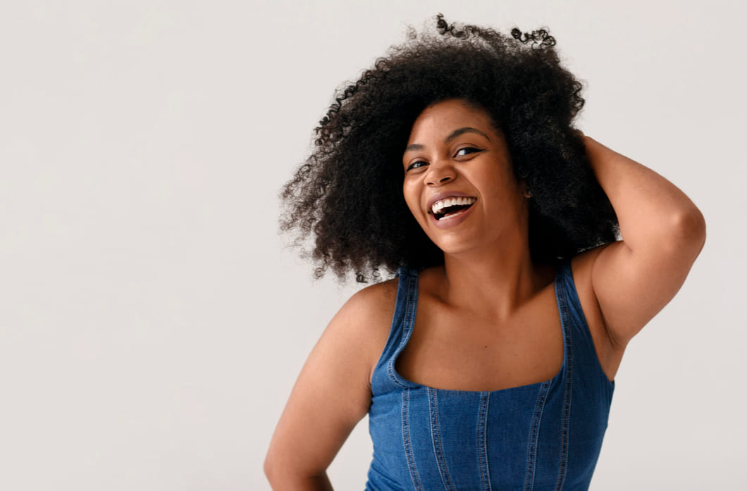 mulher-negra-usando-roupa-jeans-sobre-um-fundo-cinza-de-cabelos-crespos-representando-as-curvaturas-4a-4b-4c