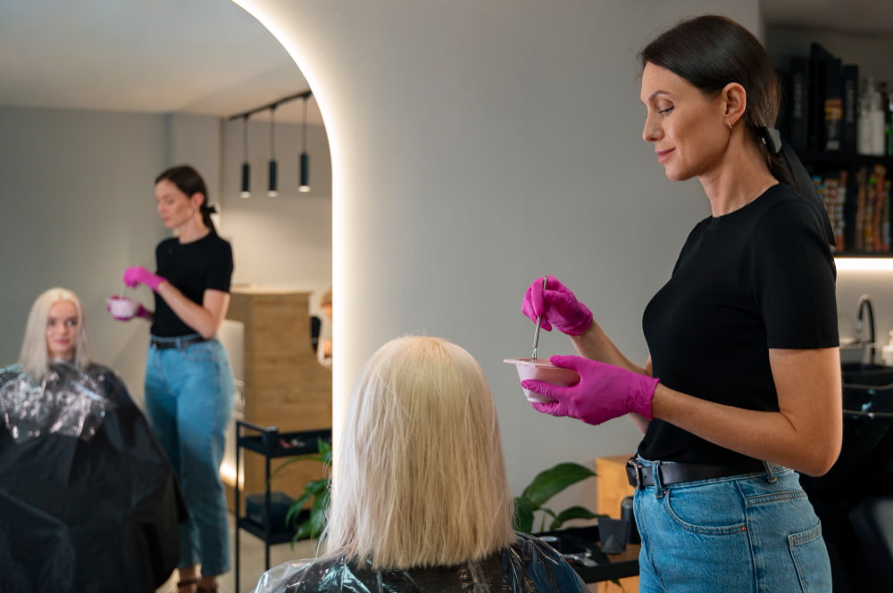 Cabeleireira tratando cabelo com corte químico de mulher loira em salão